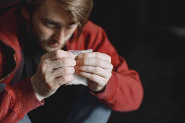 Young addicted man with cocain packet sitting alone